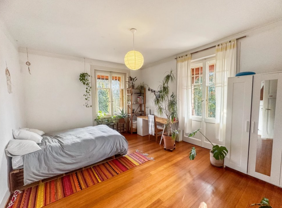 Grande chambre lumineuse avec parquet et fenêtres